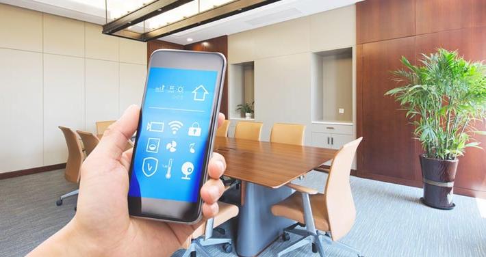 hand in office holding phone with smart office app on screen