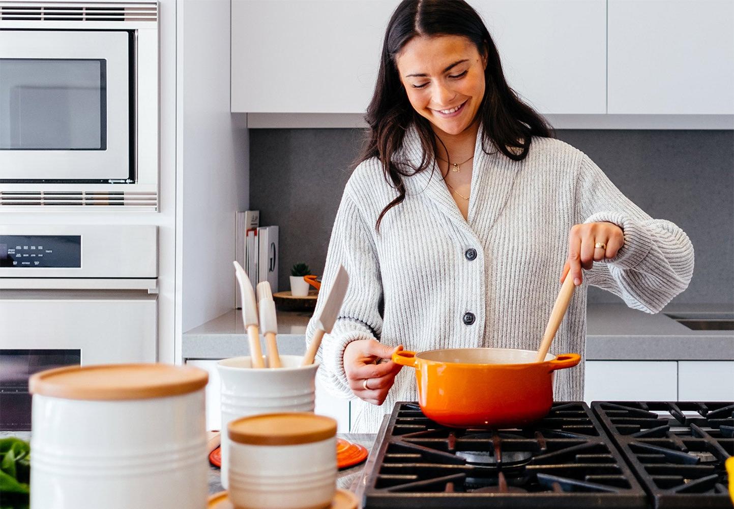 Person smiling and cooking on gas stove